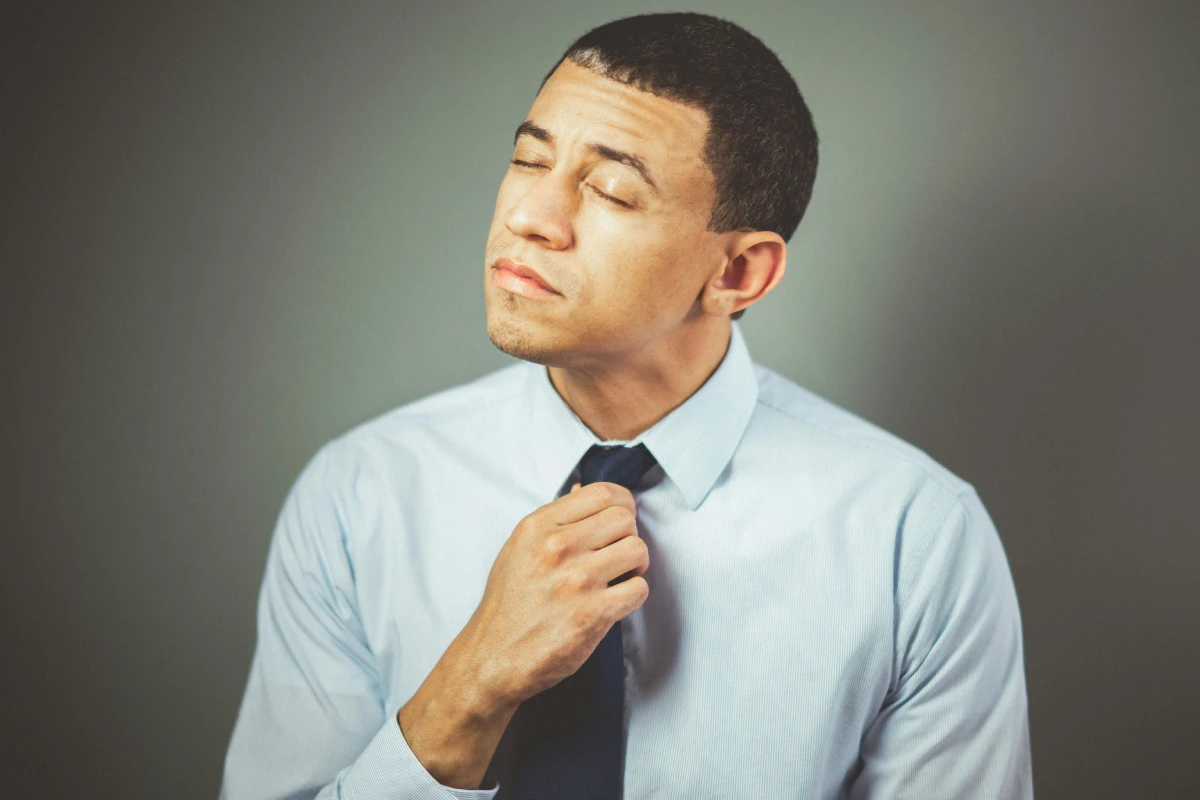 Hombre aflojándose la corbata, reflejando tensión y nerviosismo en situaciones estresantes